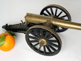 un vieux canon et une orange posés sur une surface blanche