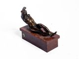 statue of a man laying on a wooden base