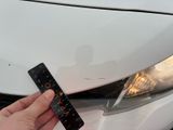 a person holding a remote control in front of a white car