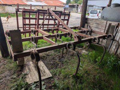 an old plow sitting in the grass next to a building