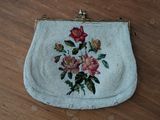 a white purse with flowers on it sitting on a wooden floor