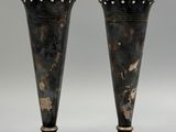 pair of antique silver vases on pedestals against a gray background