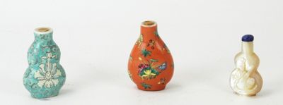 trois vases de couleurs différentes posés les uns à côté des autres sur une surface blanche