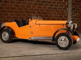 an orange vintage car parked in front of a brick wall
