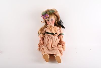 une poupée assise par terre, avec une fleur dans les cheveux