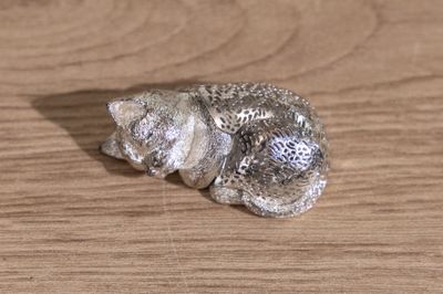 a silver figurine of a cat on a wooden table
