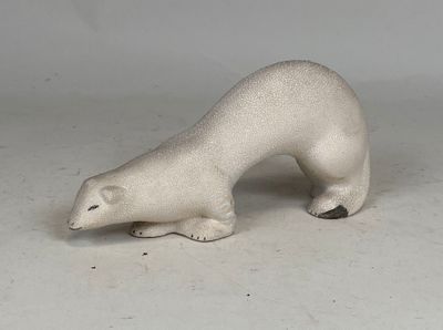 une petite figurine d'ours polaire blanc posée sur une surface blanche