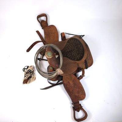 a horse saddle with a rope and a bird on the ground