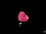 un gros plan d'un diamant rose en forme de cœur sur une surface noire