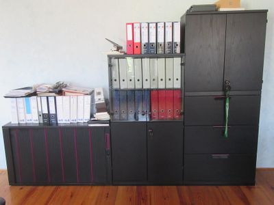 une armoire noire sur laquelle sont posés plusieurs classeurs