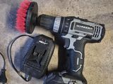 une perceuse filaire et une brosse posées par terre