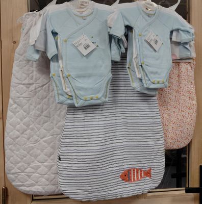 trois vêtements de bébé suspendus à un portant devant une porte