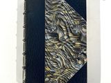 une image représentant un livre avec une couverture noire et une couverture dorée et bleue