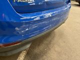 the rear end of a blue car with a sticker on it ' s bumper