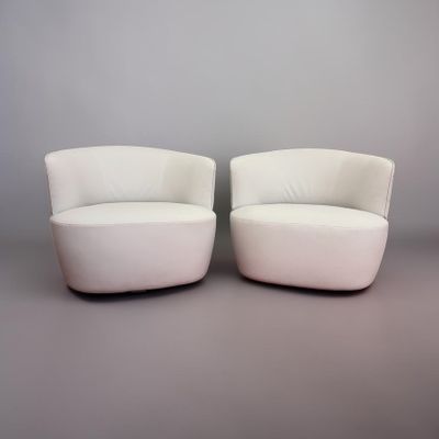 two white chairs sitting next to each other on a gray surface