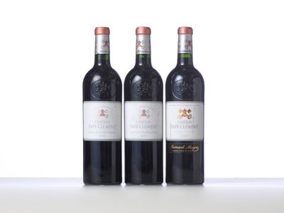 trois bouteilles de vin rouge sont alignées sur une table