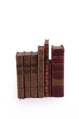 plusieurs vieux livres sont empilés sur une surface blanche