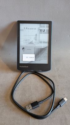 a kindle that is connected to a charger on the table