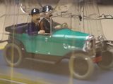 a toy car with a man and a dog in it in a glass case