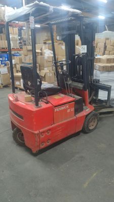 un chariot élévateur rouge chargé de cartons dans un entrepôt