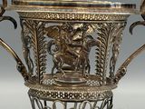 a silver vase with a horse and a man on it
