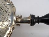 a silver plate with a black handle on a white table