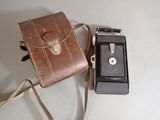 a brown bag and a black camera on a white table