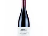 a bottle of red wine sitting on top of a white table