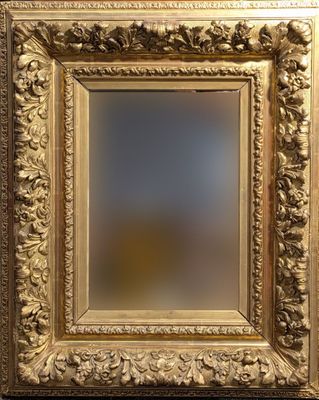 un cadre doré richement décoré, avec un miroir au centre