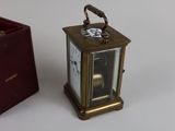 a small clock sitting next to a small box on a table