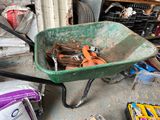 a green wheelbarrow full of tools in a garage