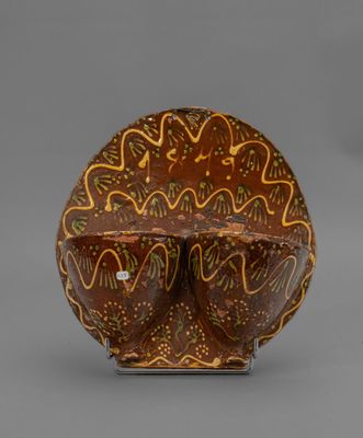 un gros plan d'un vase marron et jaune posé sur une surface grise