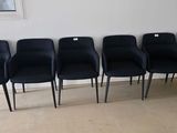 six black chairs are lined up against a wall in a room