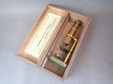 une boîte en bois contenant un microscope et une paire de ciseaux