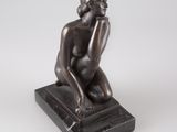 une statue en bronze représentant une femme assise sur un socle en marbre