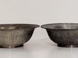 pair of silver plated bowls on stand on white surface
