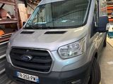 La camionnette argentée est garée dans l'entrepôt, devant une pile de cartons.