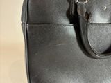 black leather briefcase sitting on top of a table with a white background