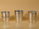 trois tasses en métal posées les unes à côté des autres sur une table