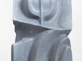 a gray sculpture that is sitting on a white surface