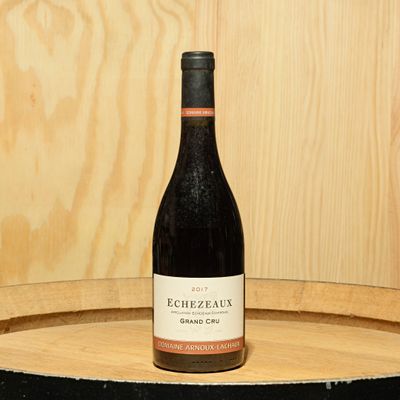 a bottle of wine sitting on top of a wooden barrel
