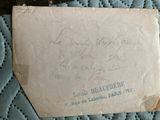 an old envelope sitting on top of a bed covered in a blue blanket