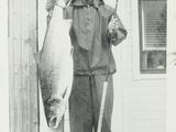 black and white photograph of a man holding a fish on a pole
