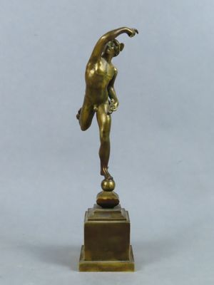 statue en bronze représentant un homme tenant une balle, posée sur un socle en bois