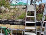Plusieurs échelles sont empilées les unes à côté des autres au bord d'une route.