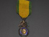 l'image d'une médaille entourée d'un ruban, posée sur une surface grise