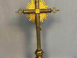 golden cross with sunburst on top of it sitting on a table