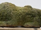 a stone sculpture of a dog on a wooden stand