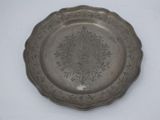 a silver plate with a design on it on a white surface