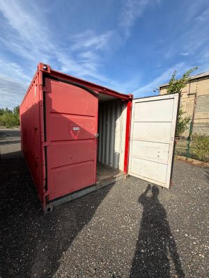 a red container sitting in the middle of a parking lot